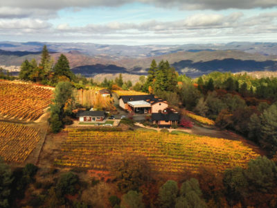 panoramic view of Robert Craig winery at the top of Howell mountain, surrounded by fall vineyards with mountains and clouds in the background