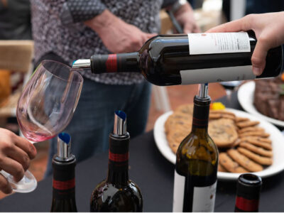 HAND POURING RED WINE OUT OF ROBERT CRAIG WINE BOTTLE WITH COOKIES IN BACKGROUND